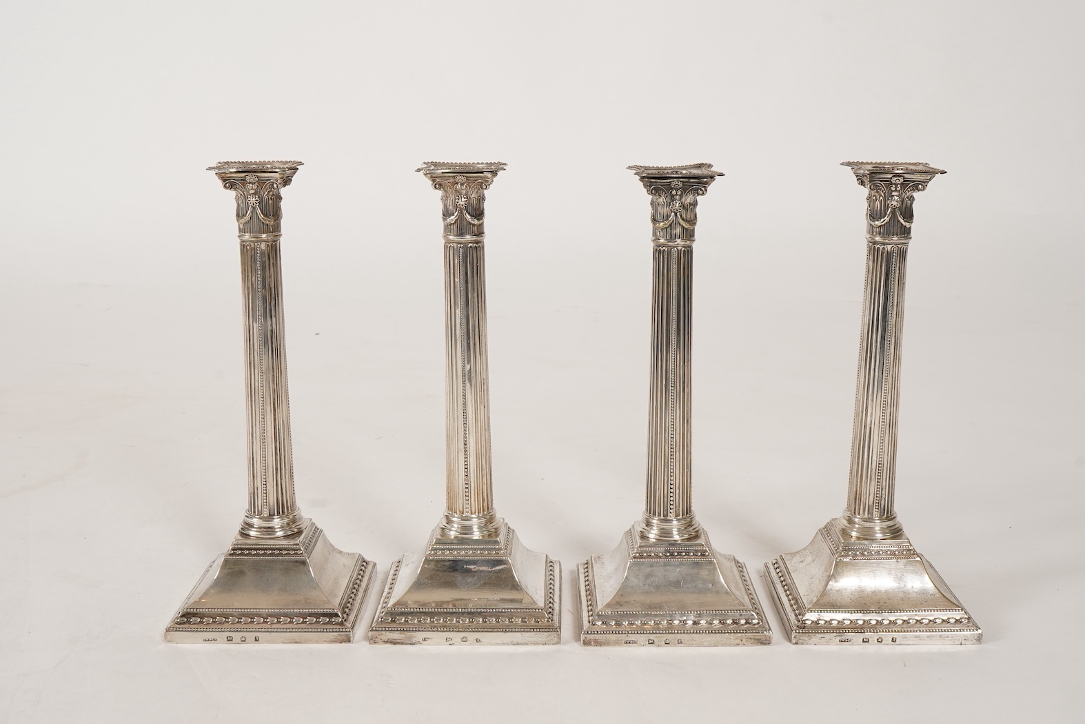 A set of four George III silver corinthian column candlesticks, by John Winter & Co